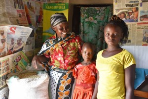 Valeria and her daughters and part of their bountiful maize harvest from ‘ngamia’ seed. Photographer: CIMMYT/Brenda Wawa